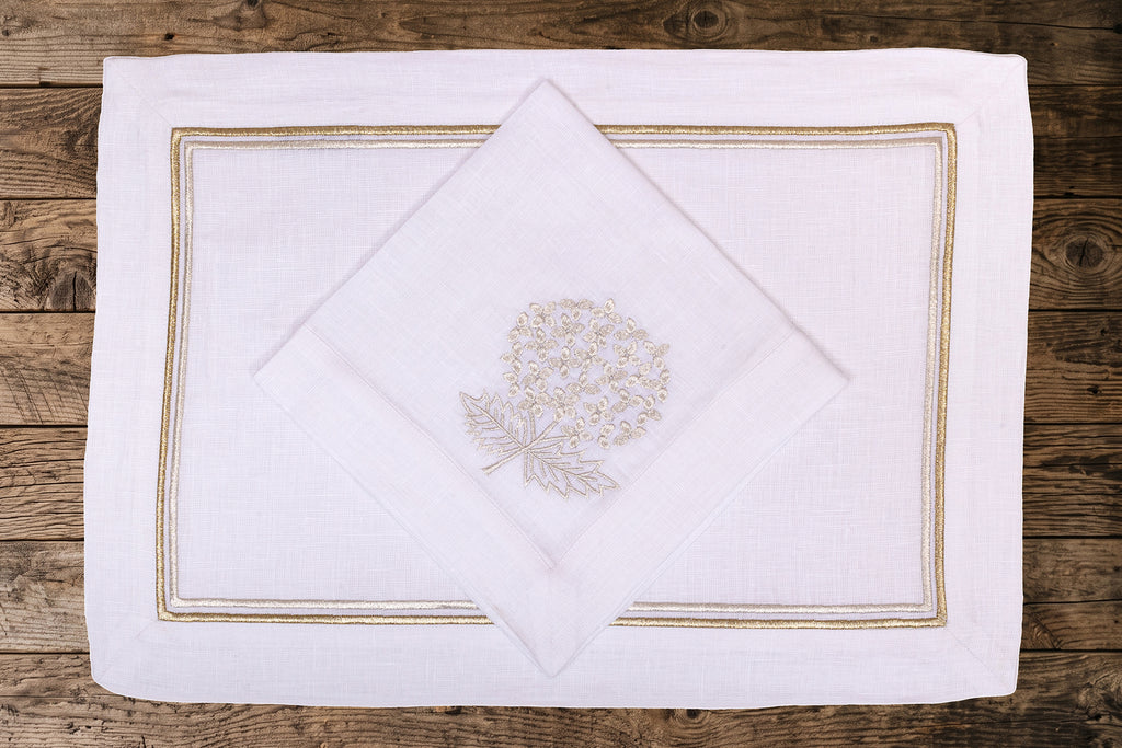White linen placemats and napkins with gold hydrangea.