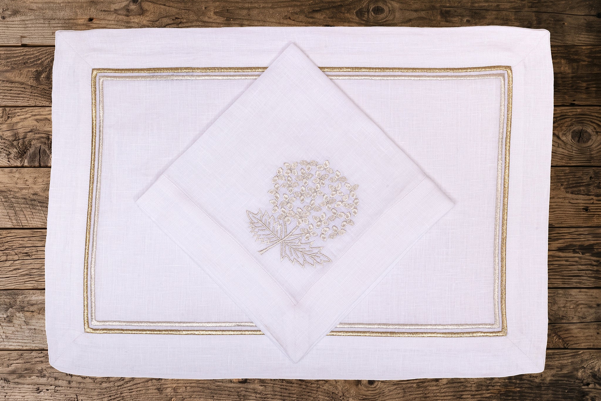 White linen placemats and napkins with gold hydrangea.