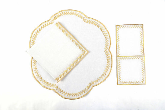 White linen gold embroidered round placemats and napkins.