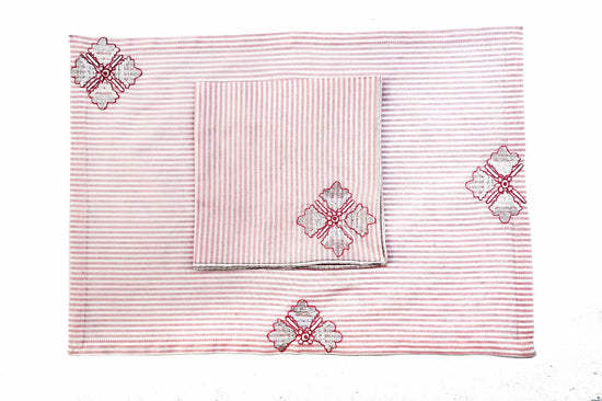 Pink striped placemats and napkins with embroidery.