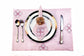 Pink striped placemats and napkins with embroidery.