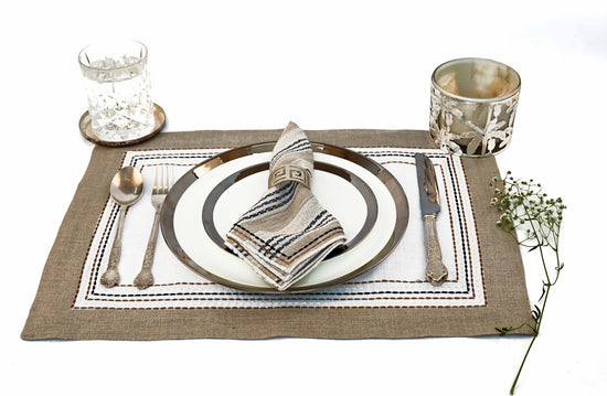 White linen placemats and beige striped napkins.