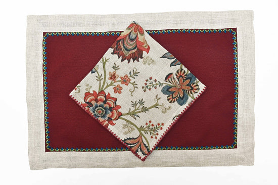 Maroon  and beige placemats  and floral printed linen napkins.