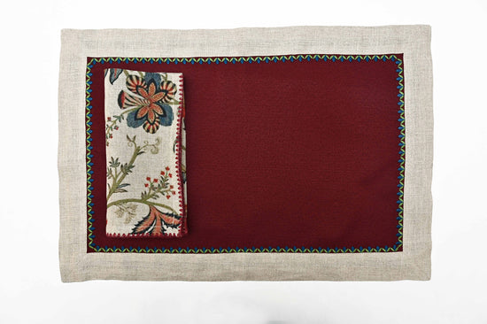 Maroon placemats with natural flange and floral printed linen napkins.