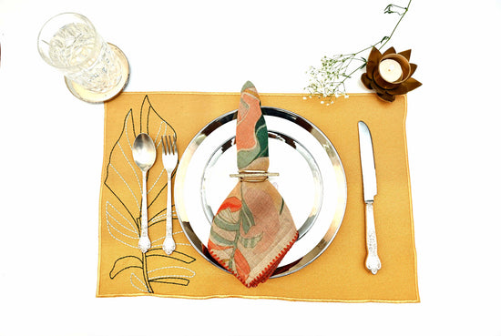 Mustard linen placemats with elaborate embroidery and printed linen napkins.