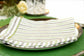 Green linen placemats with striped linen dinner napkins.