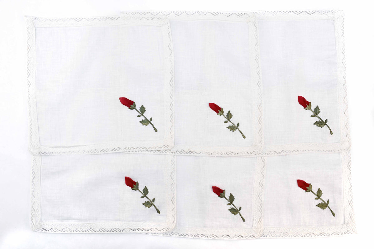 White linen dinner napkins with rosebud embroidery.