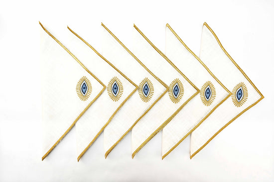 White linen cocktail napkins with gold evil eye embroidered.