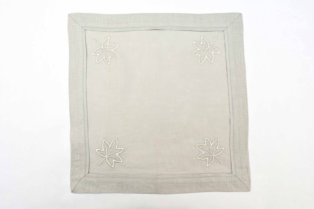 Grey linen cocktail napkins with silver maple leaf embroidery.