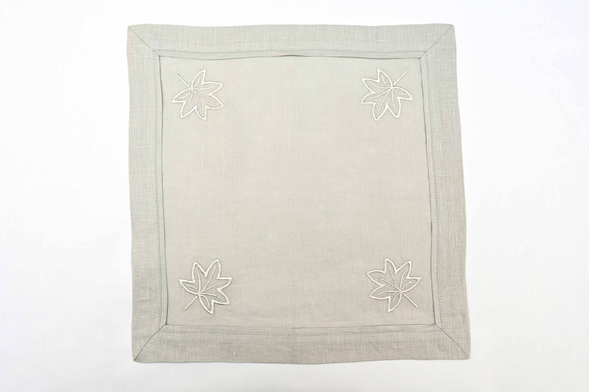 Grey linen cocktail napkins with silver maple leaf embroidery.