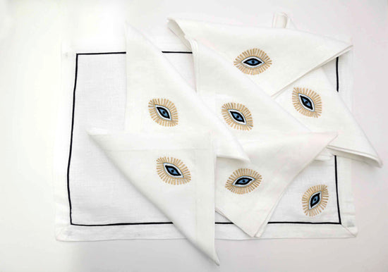 White linen placemats and napkins with Gold evil eye embroidered.