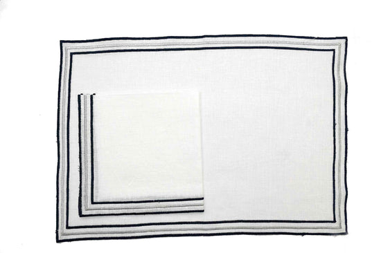 White linen placemats and napkins with embroidery.