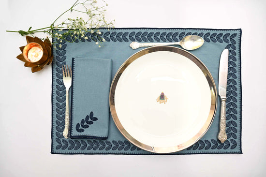 Blue cotton placemats with  embroidered border with blue linen napkins.