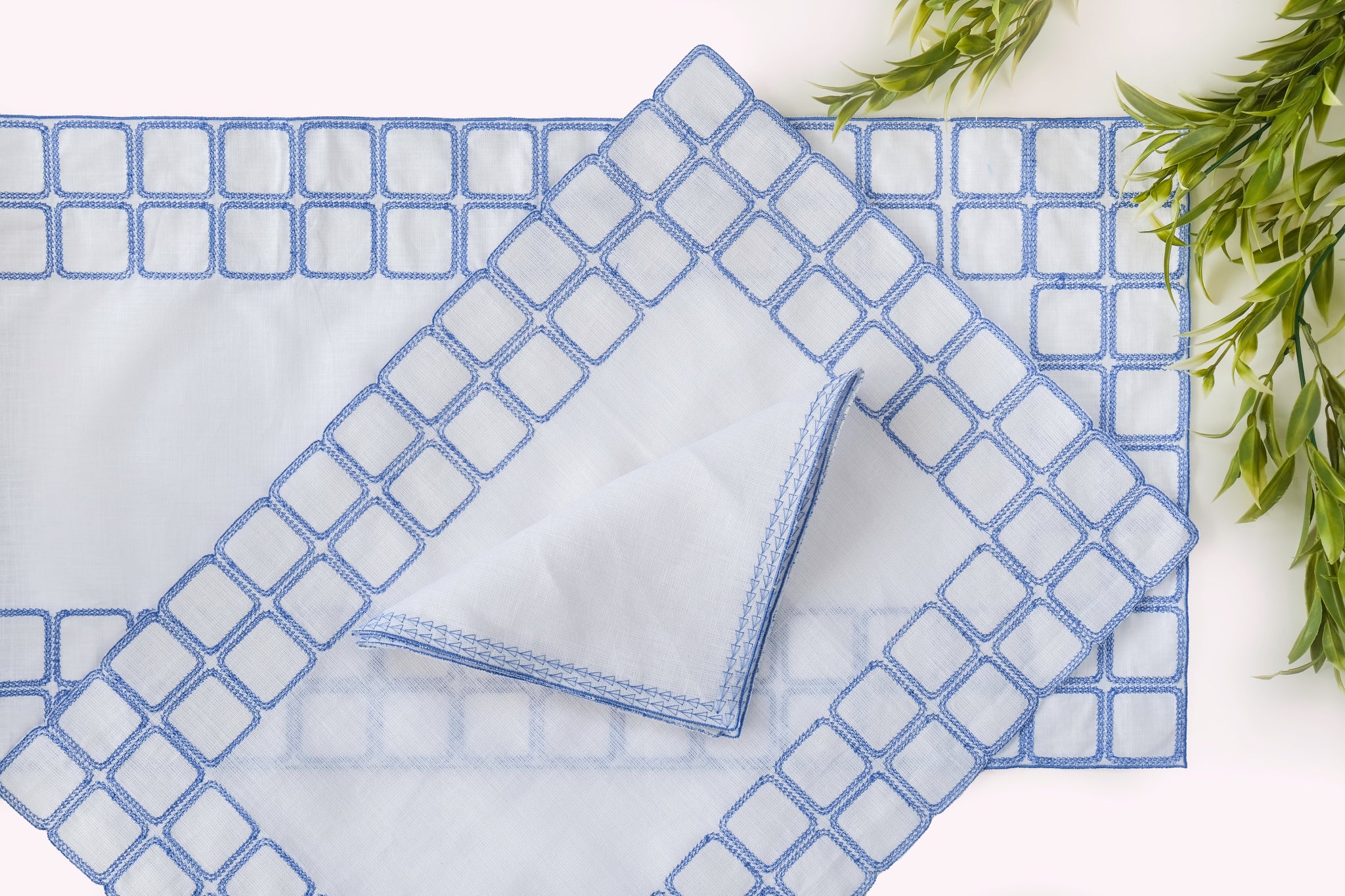 White linen runner with blue embroidery.
