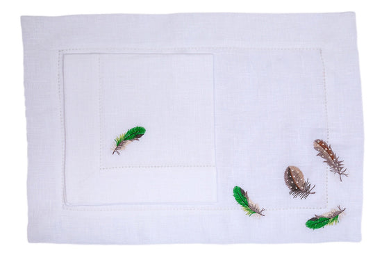White linen embroidered placemats with embroidered napkins.