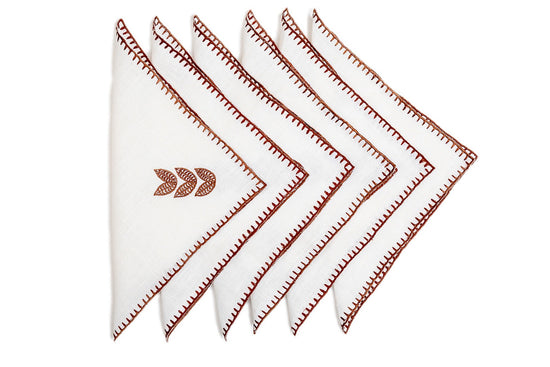 White linen cocktail napkin with brown leaf embroidery.