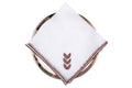 White linen dinner napkins with brown leaf embroidery.