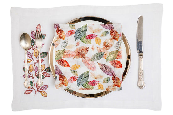 White placemats with multicolored embroidery with linen printed napkins.