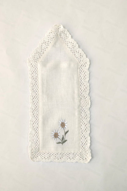 White linen  cutlery holder with floral embroidery.