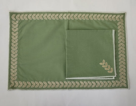 Green cotton placemats with embroidered border with  linen napkins.