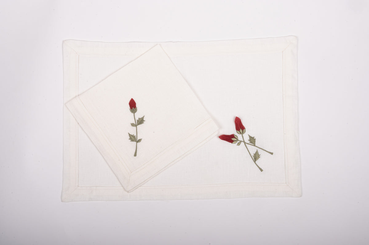 White linen placemats  and napkins with rosebud embroidery.