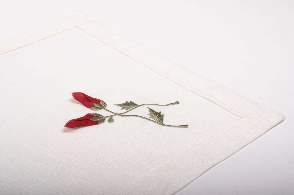White linen placemats  and napkins with rosebud embroidery.