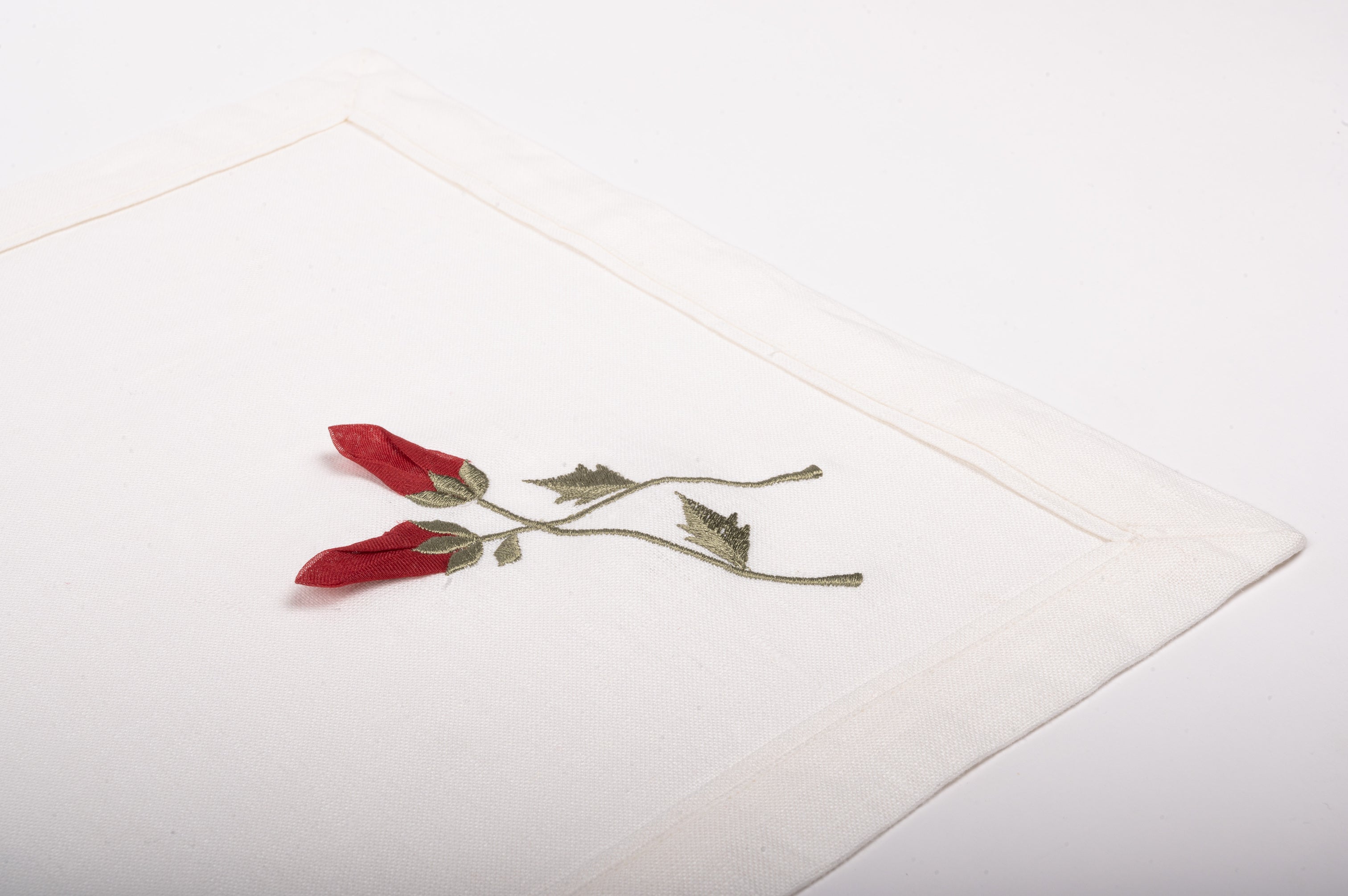 White linen placemats  and napkins with rosebud embroidery.