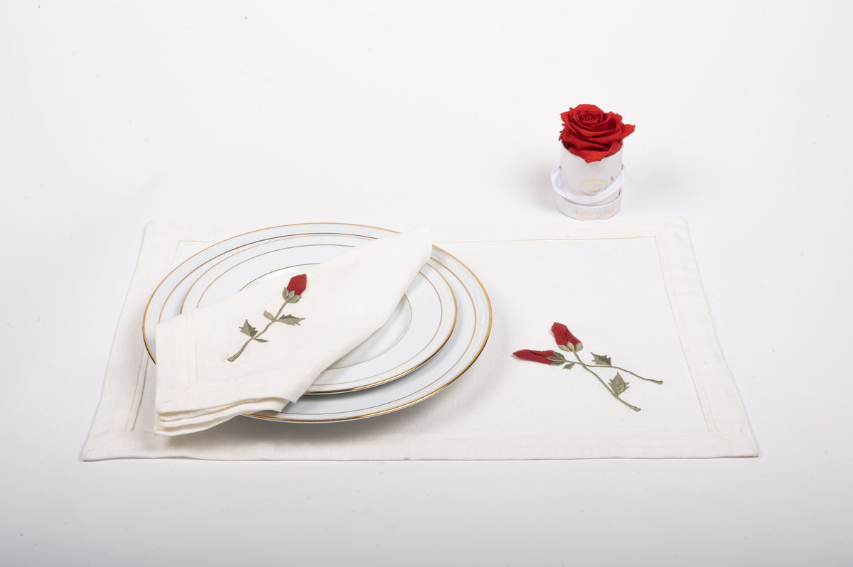 White linen placemats  and napkins with rosebud embroidery.