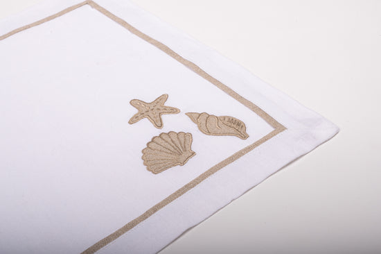 White linen placemats  and napkins with appliqued shell  embroidery.