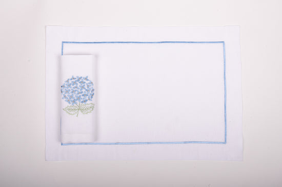 White linen placemats with blue embroidery and napkins with embroidered hydrangea.