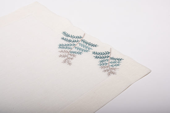 White linen placemats and napkins with fern leaf embroidered.