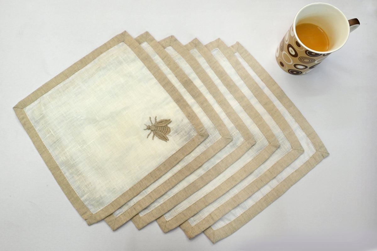 White linen cocktail napkins with an  embroidered beetle