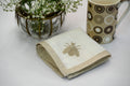 White linen cocktail napkins with an  embroidered beetle