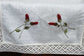 White linen runner with rosebud embroidery and lace detailing.
