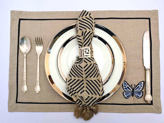 Natural linen placemats with butterfly and blue striped napkins with tassels.