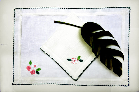 White linen with pink and white floral placemats and napkins with green picoting.