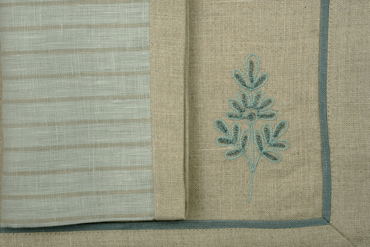 Natural coloured  embroidered linen placemats  and blue and natural striped linen napkins.