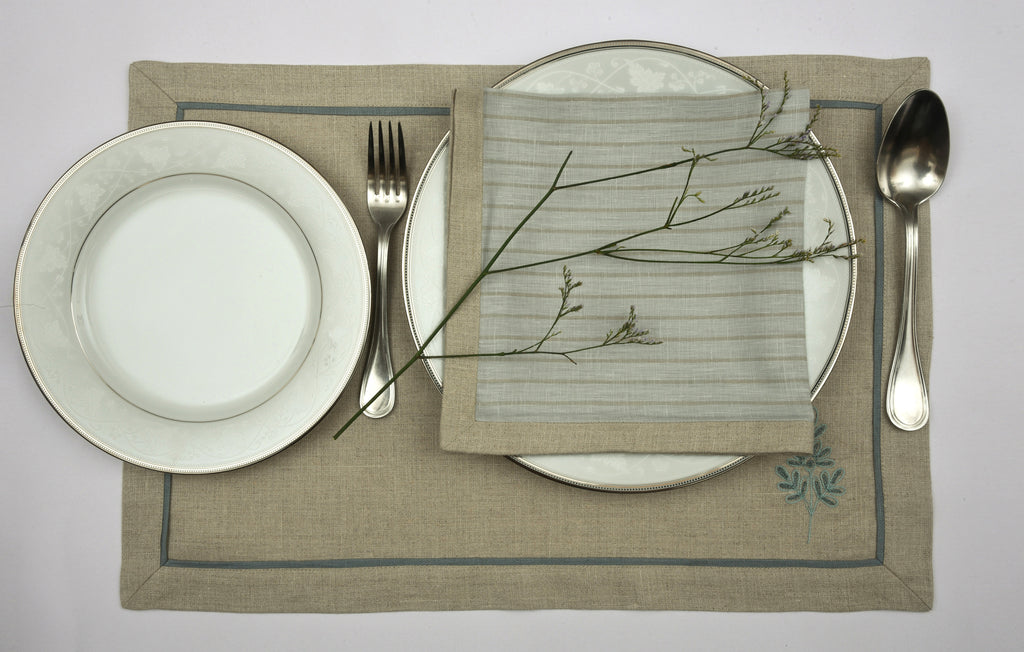 Natural coloured  embroidered linen placemats  and blue and natural striped linen napkins.