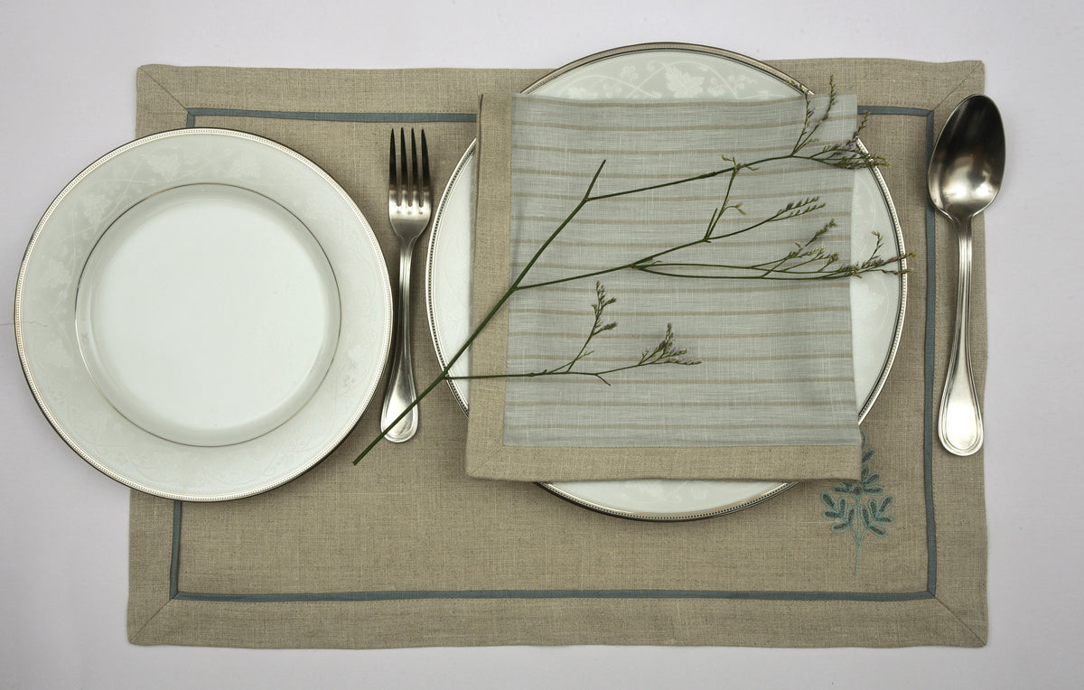 Natural coloured  embroidered linen placemats  and blue and natural striped linen napkins.