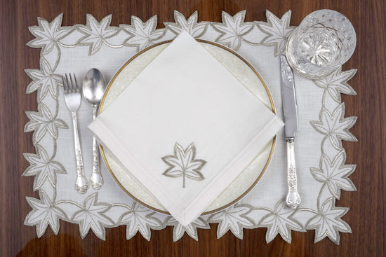 White linen placemats and napkins with gold cutwork embroidery.