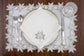 White linen placemats and napkins with gold cutwork embroidery.
