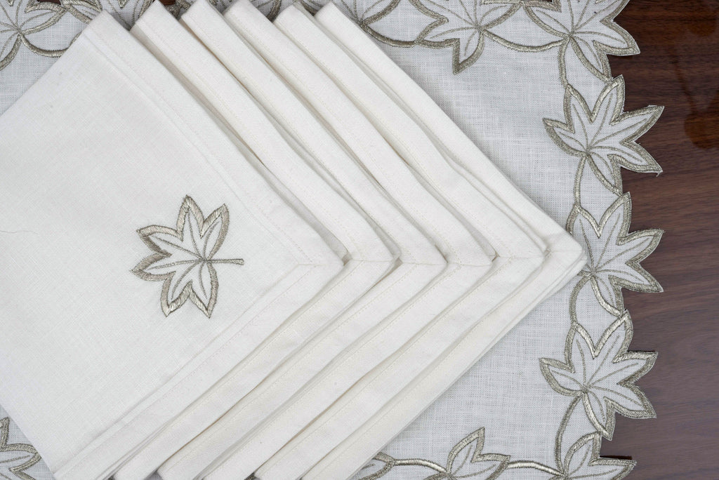 White linen placemats and napkins with silver cutwork embroidery.