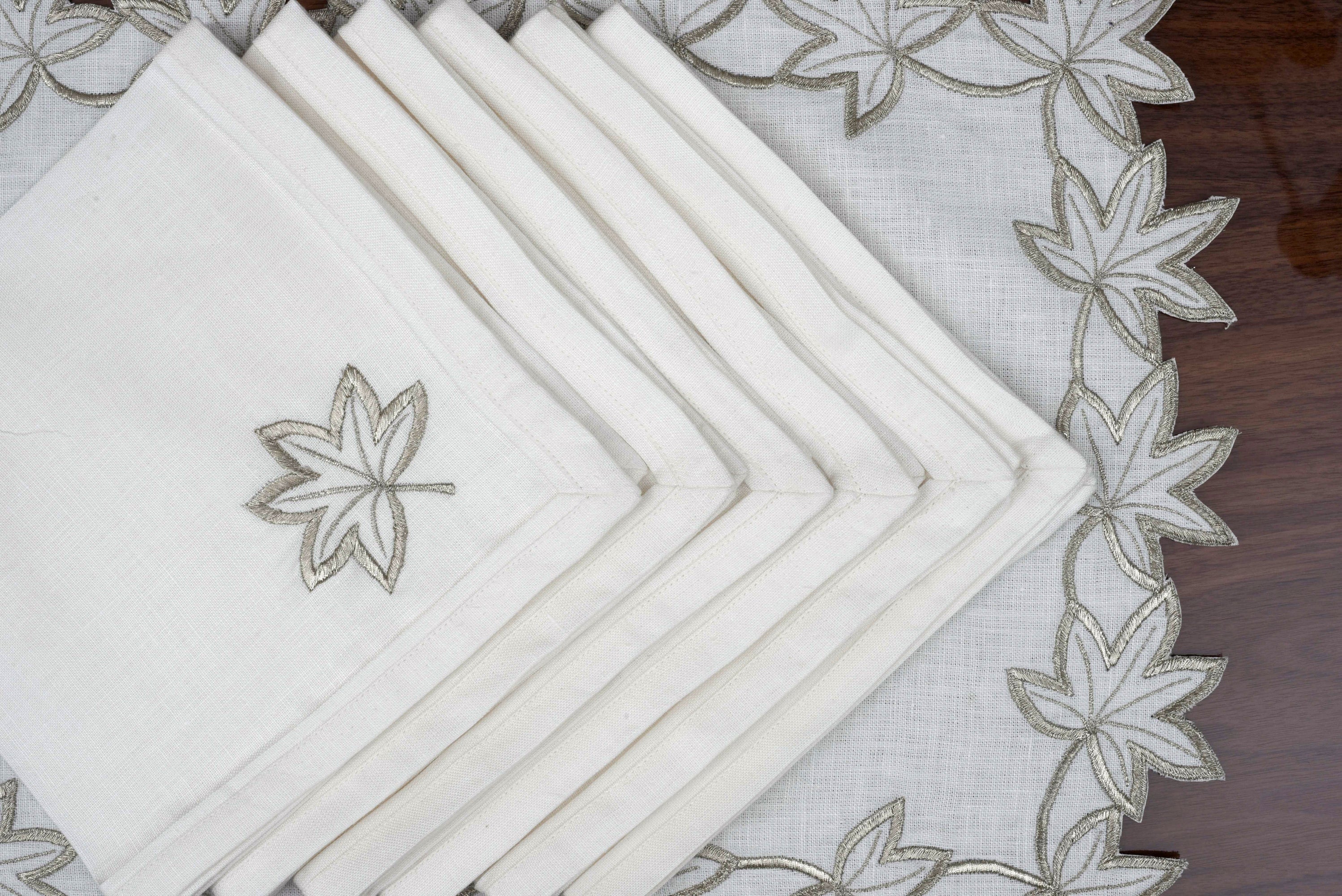 White linen placemats and napkins with silver cutwork embroidery.