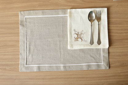 White linen napkins with regal motif and natural brown linen mats with white piping.