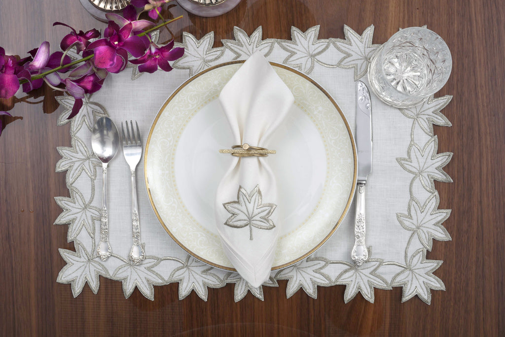 White linen placemats and napkins with silver cutwork embroidery.