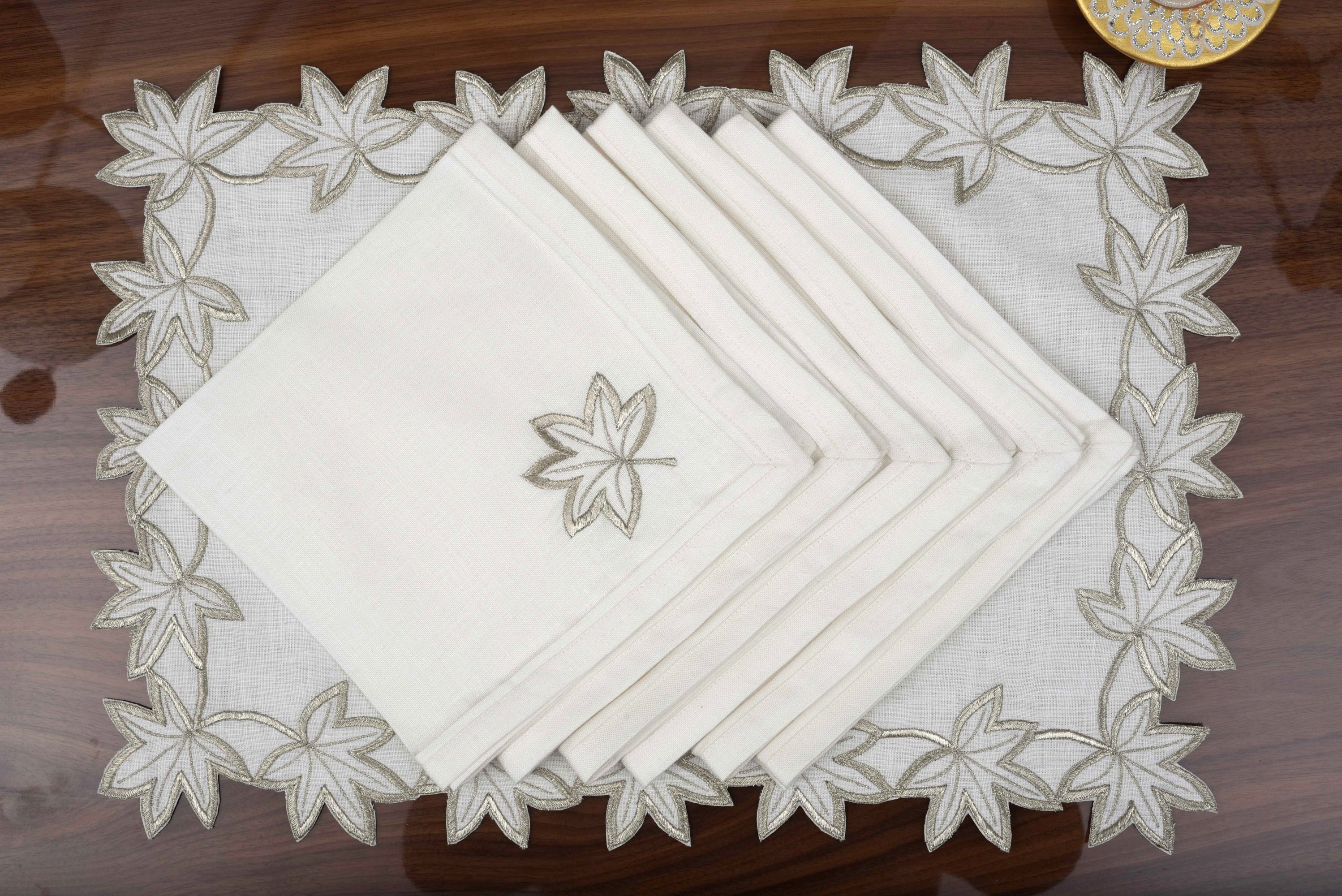 White linen placemats and napkins with silver cutwork embroidery.